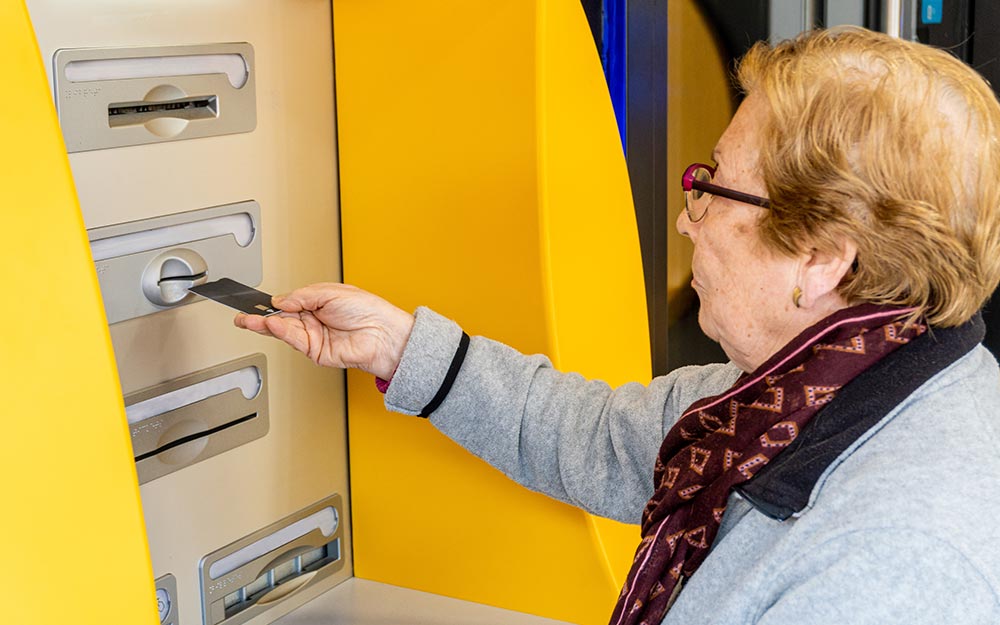 Una persona mayor interactua con un cajero automático.