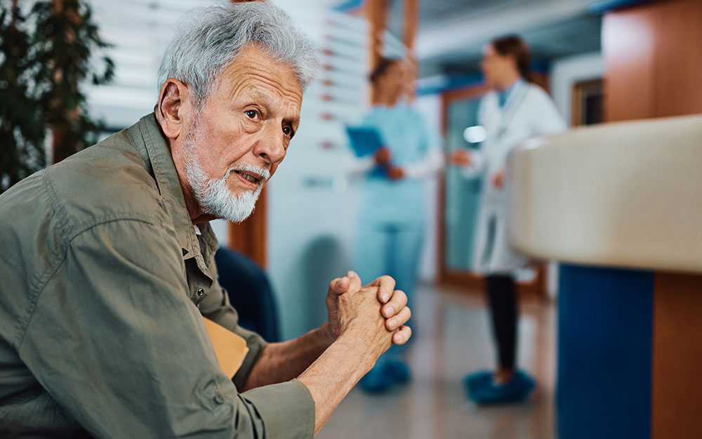 Una persona con gesto de impaciencia espera sentado en una clínica.