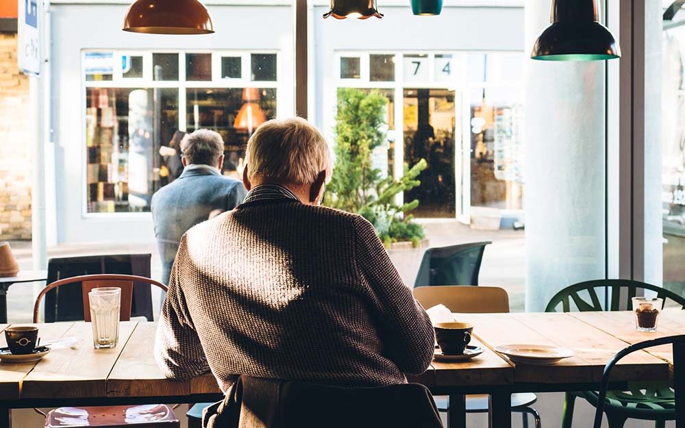 Una persona mayor sentada en una cafetería.