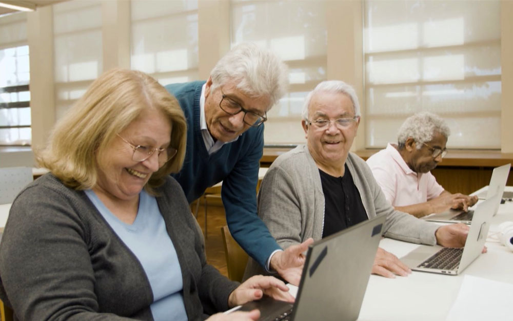 Varias personas mayores trabajan ante sus ordenadores portátiles.