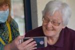 Una persona mayor mira un teléfono móvil.