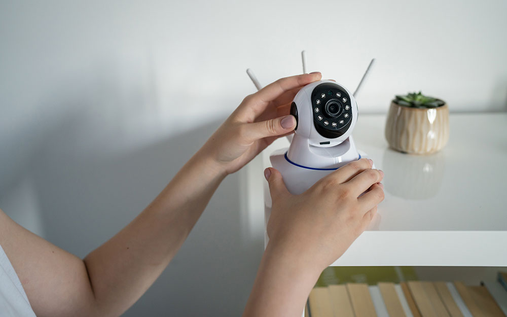 Una persona colocando una cámara de videvigilancia en una estantería