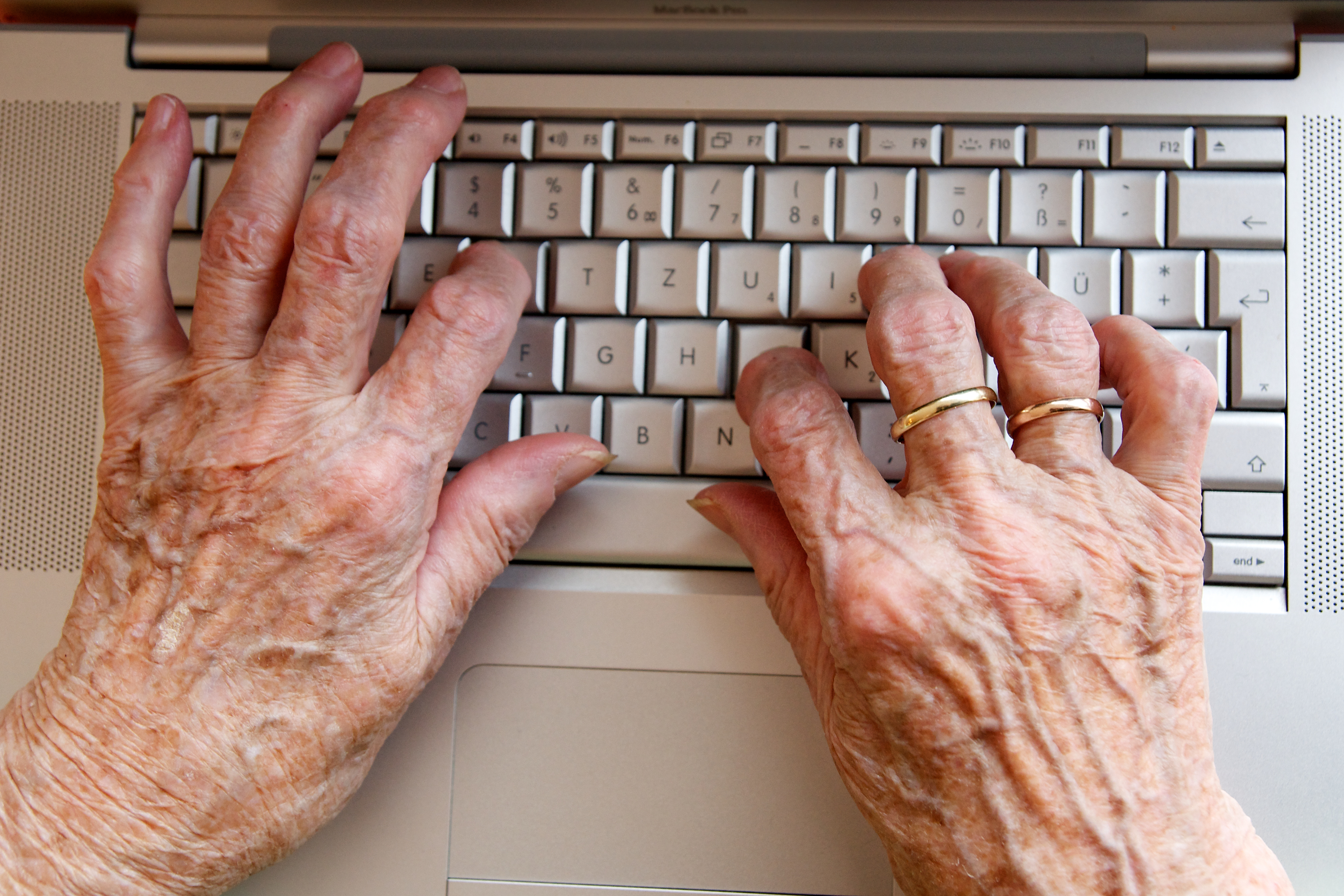 Manos de una persona mayor tecleando un ordenador