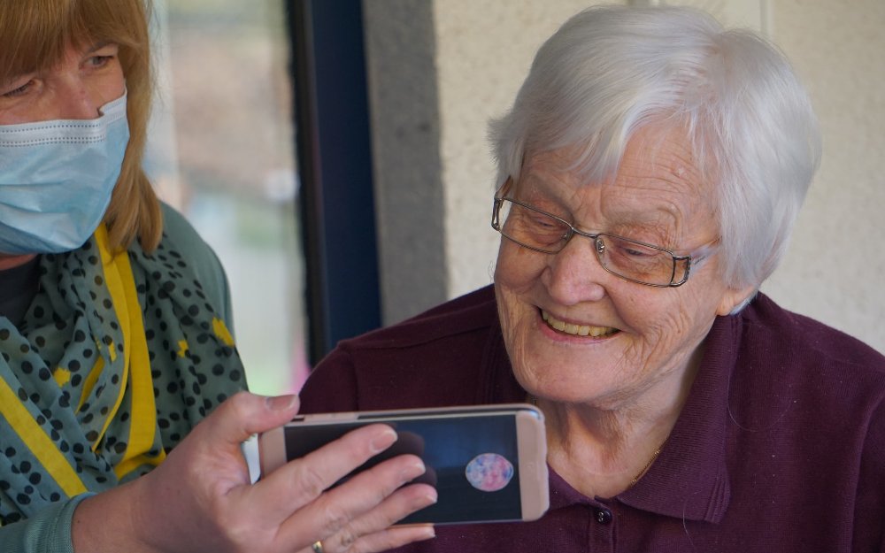 Una persona mayor mira un teléfono móvil.