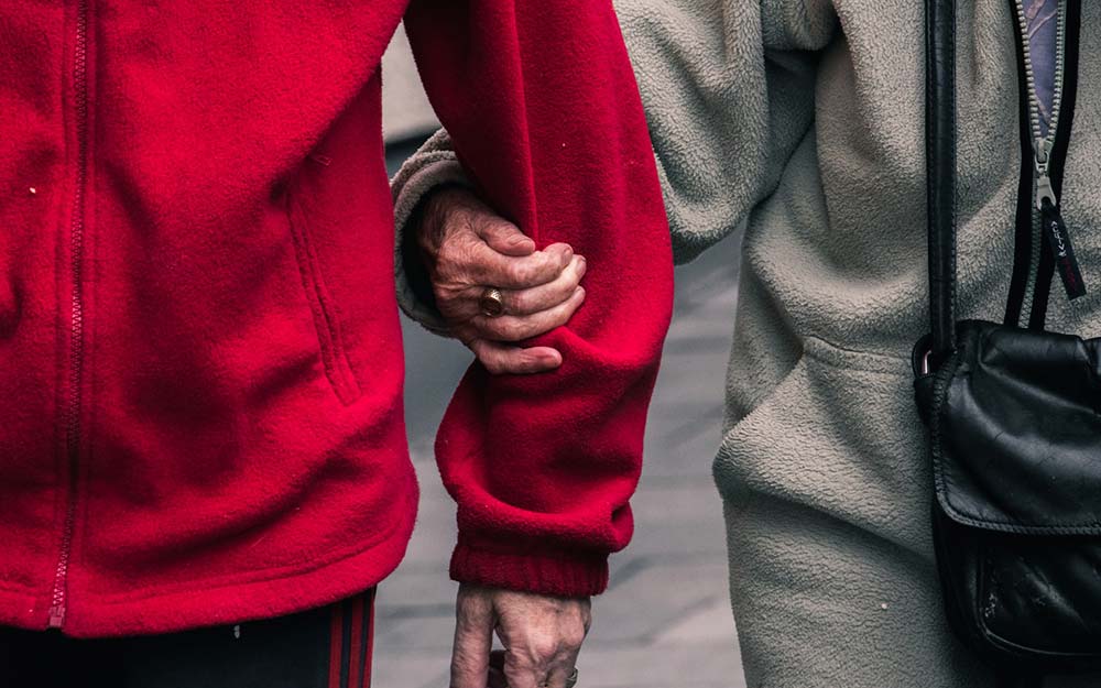 Dia Mundial de Toma de Conciencia del abuso y el maltrato en la vejez Dos personas mayores caminan agarradas del brazo.
