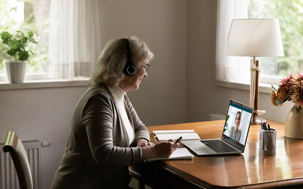 Una mujer toma notas mientras atiende una videoconferencia