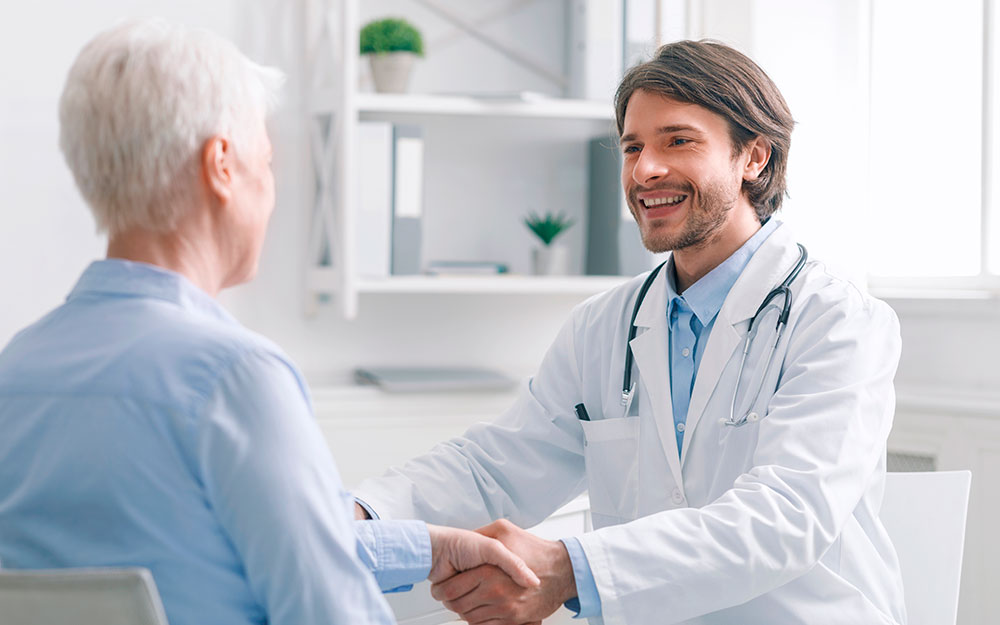 Ha llamado a “construir políticas de salud más eficaces" Un médico sostiene la mano de una persona mayor.