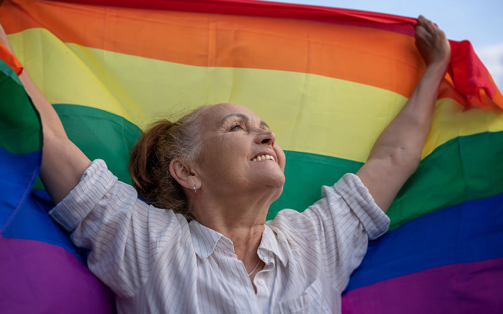 Una mujer sostiene en alto una bandera LGTBI