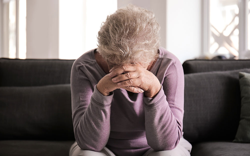 En el marco del Día Mundial de la Salud Mental una mujer sentada apoya su cabeza sobre sus manos