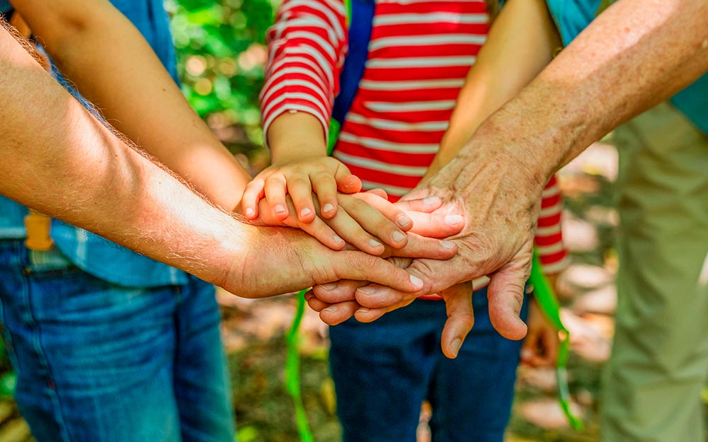 Un grupo de personas de todas las edades unen sus manos en el centro