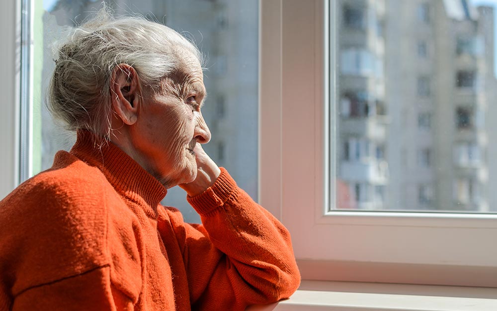 Una mujer mayor mira a través de una ventana.