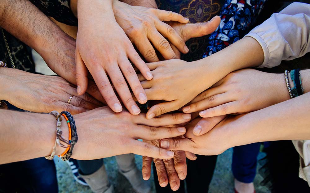 Un grupo de personas de diferentes edades unen sus manos