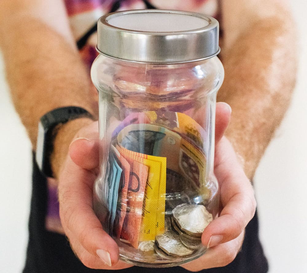 Durante el V Encuentro de Economía Senior Unas manos sujetando un bote de cristal con dinero en el interior