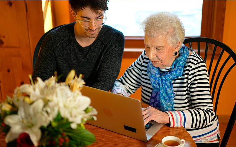 Una mujer maneja un ordenador junto acompañada por un joven.
