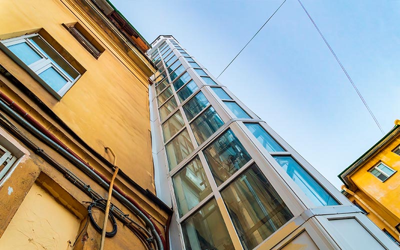 Miles de personas se ven obligadas a la institucionalización ante la falta de una vivienda digna y accesible Edificio de viviendas antiguo con ascensor exterior añadido