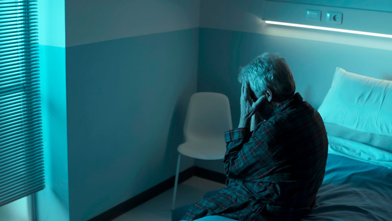 Recalca que debe abordarse en el marco de la coordinación sociosanitaria Persona mayor sola sentada en la cama de una habitación de hospital