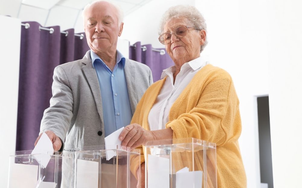 Un hombre y una mujer depositan sus votos en una urna