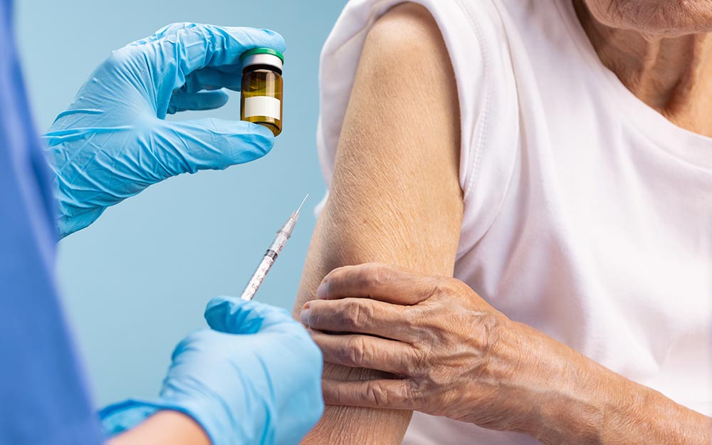Un asistente sanitario administra una vacuna a una mujer mayor