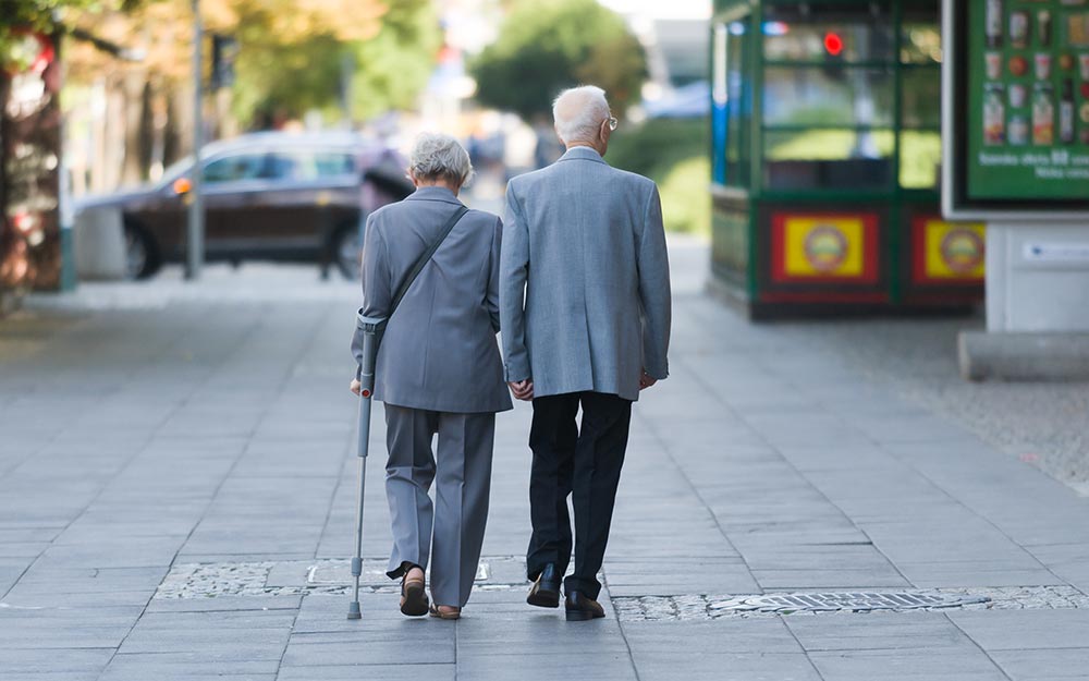 Dos personas mayores pasean solas por la calle.