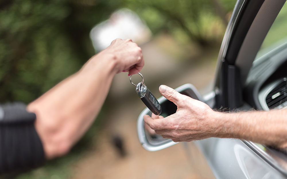 Una persona entrega a otra la llave de un coche.