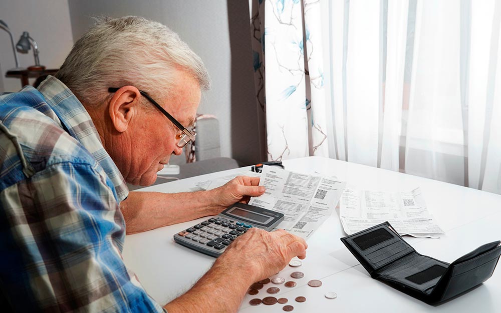 Una persona mayor revisa facturas con una calculadora