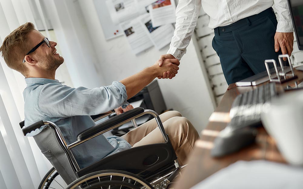 Una persona en silla de ruedas da la mano a otra.