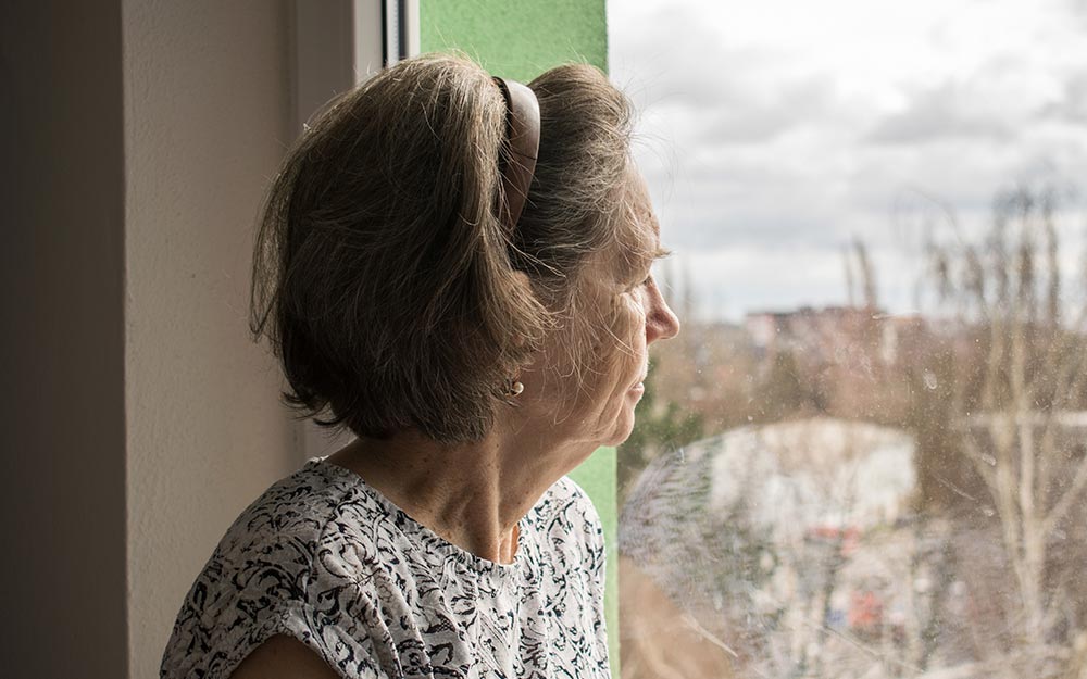 En el marco del Día Internacional de la Eliminación de la Violencia contra la Mujer Una mujer mira a través de una ventana.