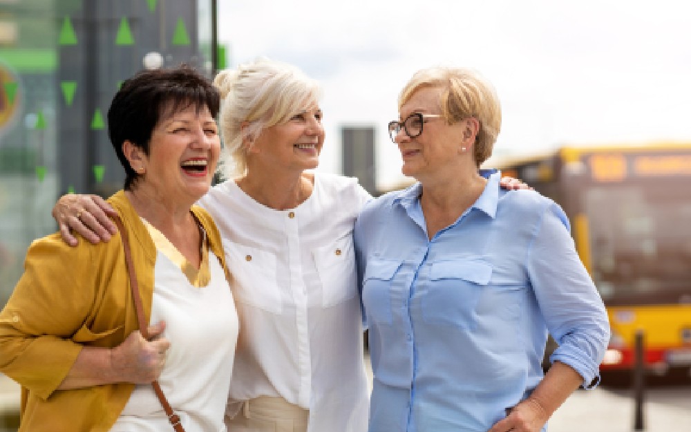 Tres mujeres mayores conversan y se ríen juntas.