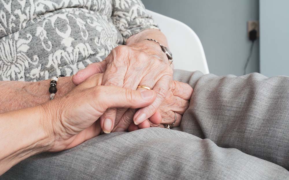 La mano de una persona sujeta la de una persona mayor