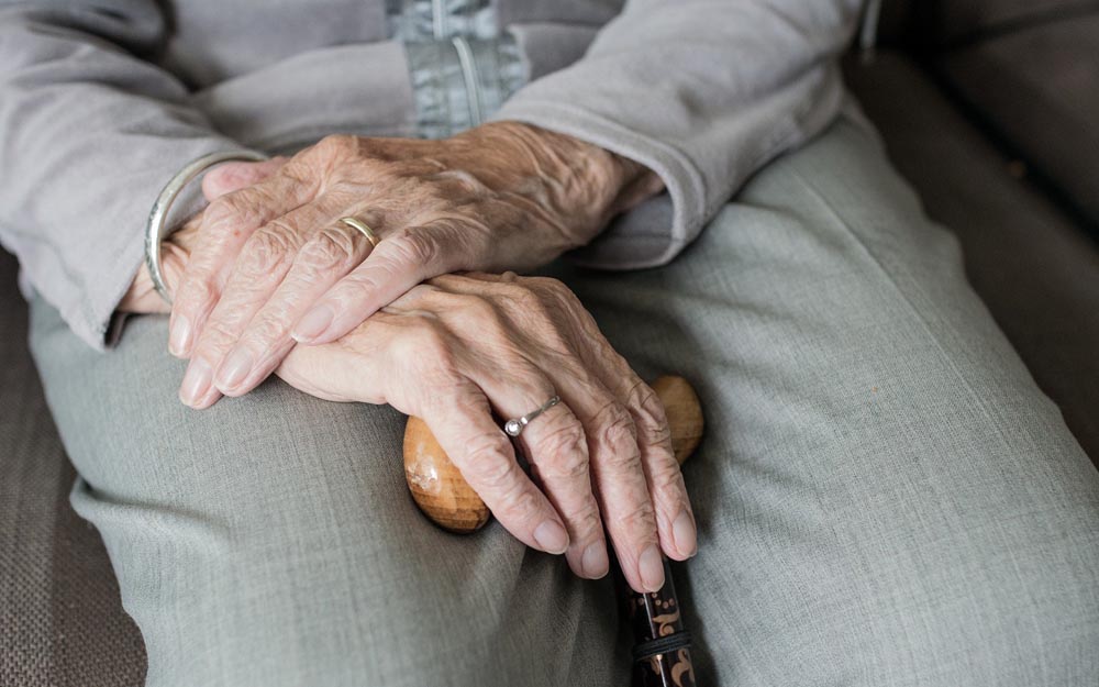 Manos de una persona anciana apoyadas en el bastón