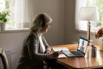 Una mujer toma notas mientras atiende una videoconferencia