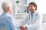 Un médico sostiene la mano de una persona mayor.