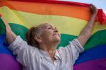 Una mujer sostiene en alto una bandera LGTBI