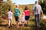 Una abuela y un abuelo caminan por el campo junto a sus tres nietos