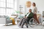 Una mujer mayor en silla de ruedas junto a su cuidadora