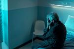 Persona mayor sola sentada en la cama de una habitación de hospital 
