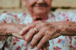 Imagen de las manos de una mujer mayor con una alianza.