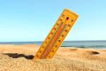 Un termómetro semienterrado en la arena de una playa