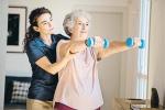Chica joven ayudando a una mujer mayor a hacer ejercicio con unas mancuernas