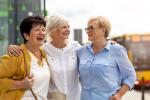 Tres mujeres mayores conversan y se ríen juntas.