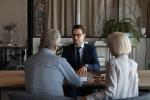 Un profesional de la banca atiende, en una mesa, a dos personas mayores.