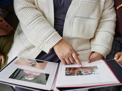 Una persona mayor enseña un álbum de fotos a otras dos personas