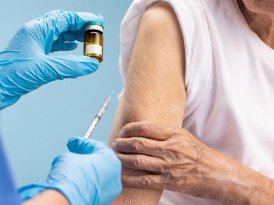 Un asistente sanitario administra una vacuna a una mujer mayor