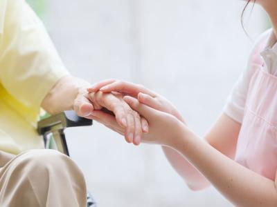 Una persona cuidadora sujeta la mano de una persona mayor.