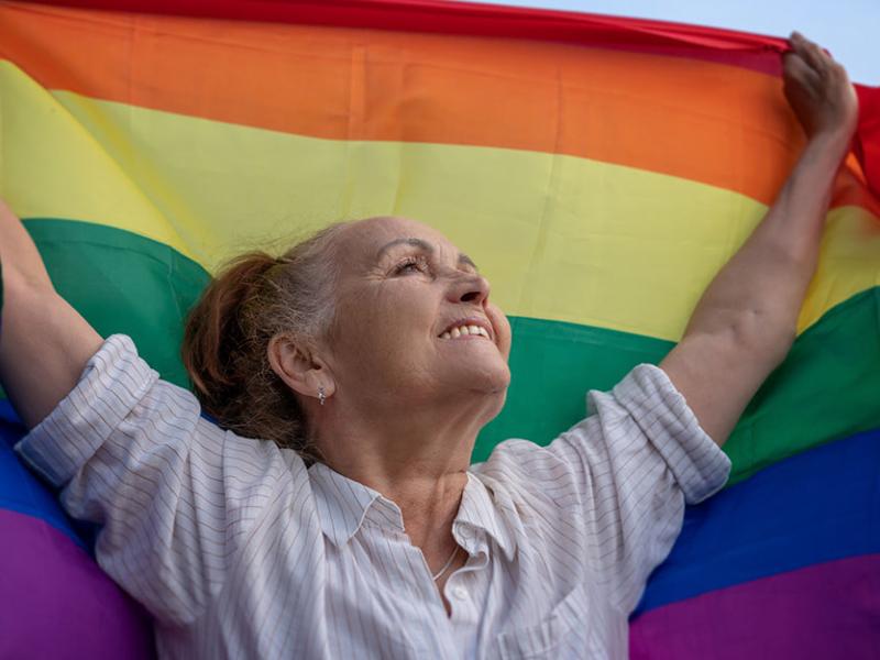 Una mujer sostiene en alto una bandera LGTBI