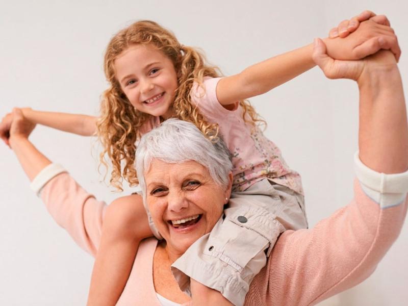 Una mujer mayor sostiene a una niña sobre sus hombros