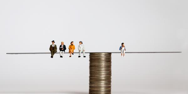 Balanza sobre monedas con una persona a la derecha que representa la población activa y al izquierda personas mayores jubiladas