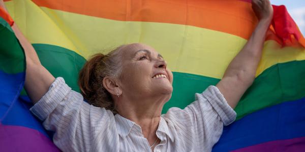 Una mujer sostiene en alto una bandera LGTBI