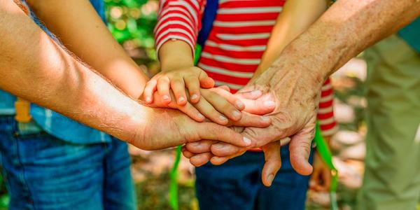 Un grupo de personas de todas las edades unen sus manos en el centro