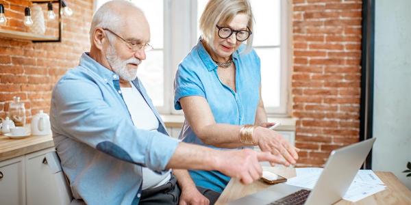 Una pareja de personas mayores consultan información en un ordenador